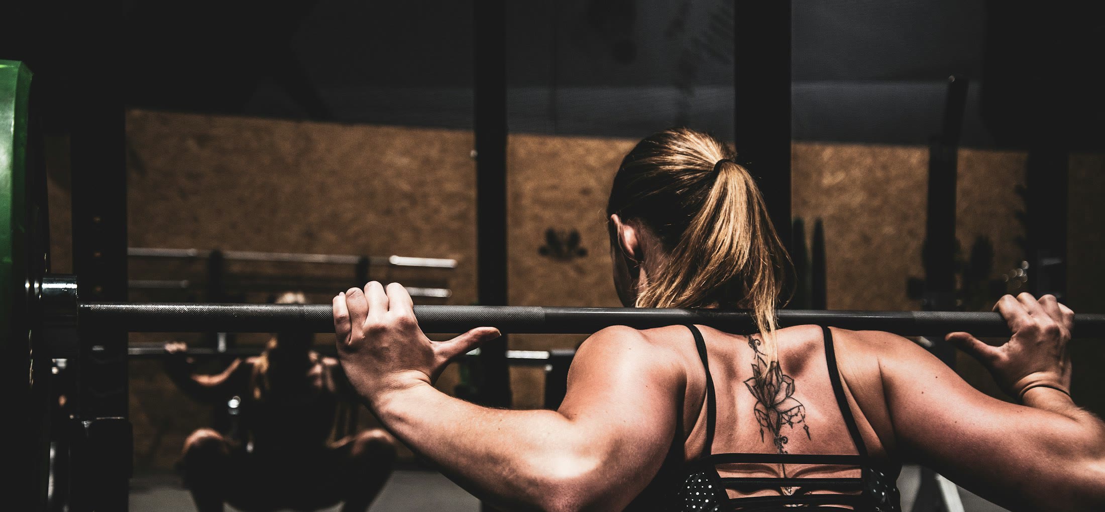 A woman gripping a barbell in a dim studio